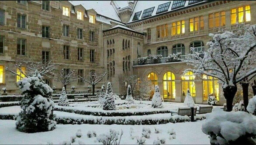 Cour d'un lycée parisien sous la neige, fenêtres éclairées en fin de journée